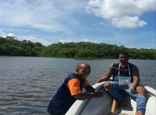 Dos integrantes de la comunidad en una lancha sobre la ciénaga, con el manglar al fondo